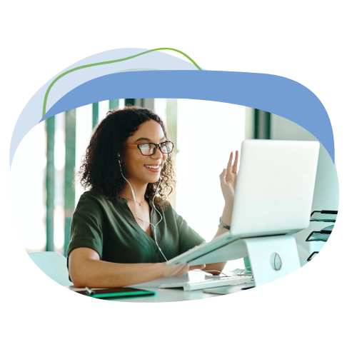 A smiling educator on a video call from her desk, waving at the camera